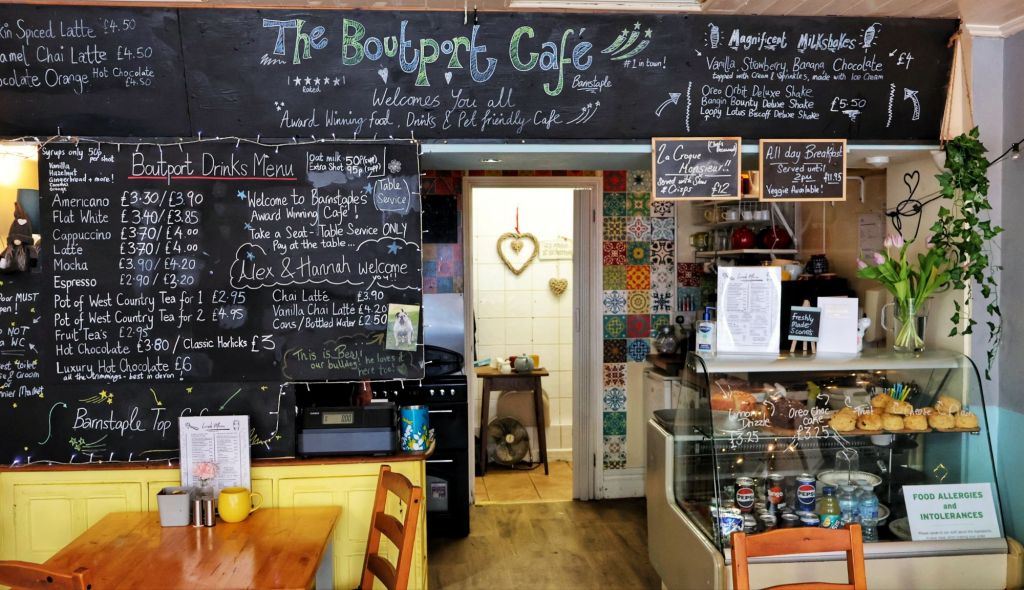 Interior view of the Boutport Cafe, showcasing the chalkboard menu, drinks selection, and cozy seating arrangement.